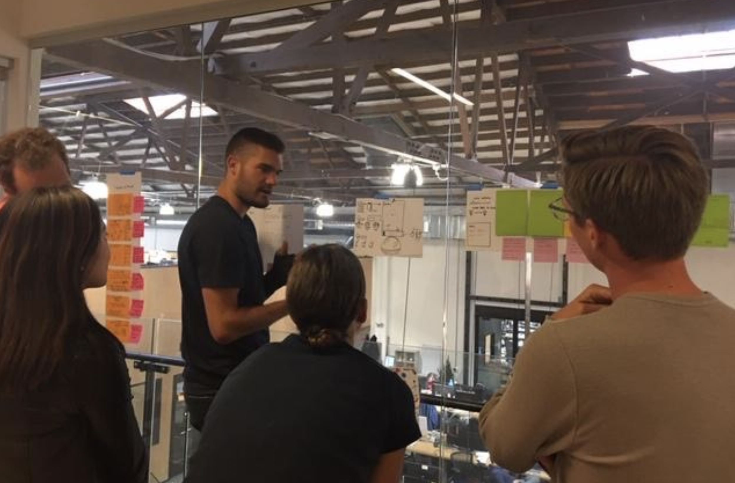 Image of Brian standing in front of a whiteboard with his team during the design sprint.